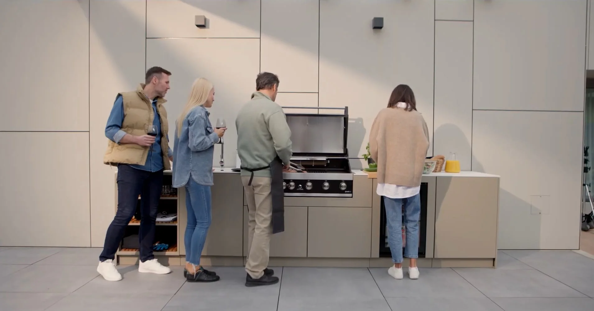 Bezoekers bekijken een crème buitenkeuken met inbouwbarbecue